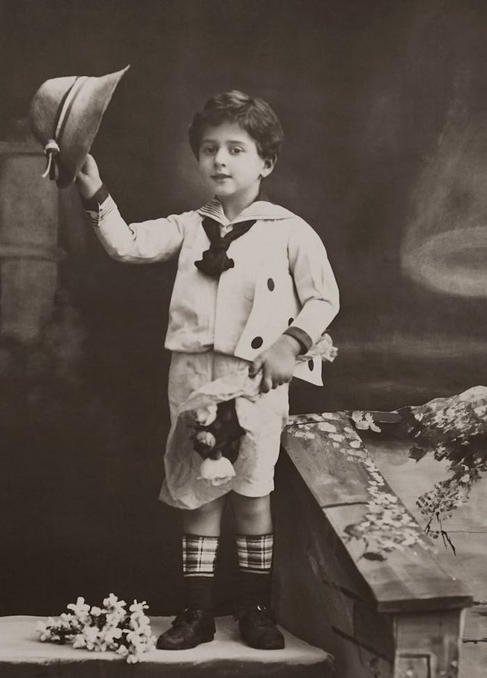 Charming vintage portrait of a young boy holding a hat and flowers, reflecting nostalgia.